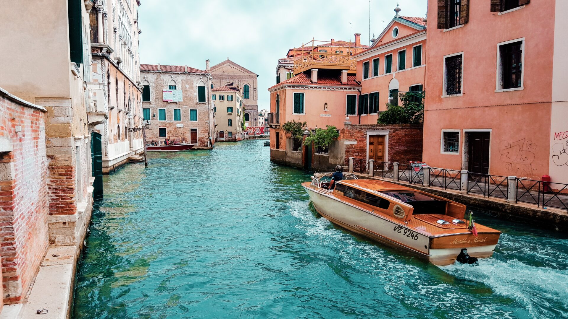 orange-powerboat-between-medium-rise-buildings-208701